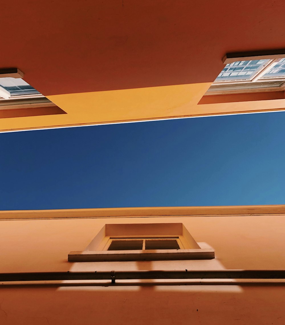 낮에 푸른 하늘 아래 갈색 콘크리트 건물의 로우 앵글 사진