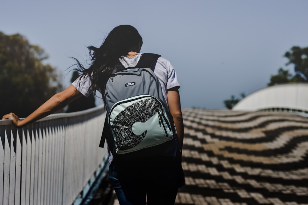 Frau geht mit Rucksack an der Brücke