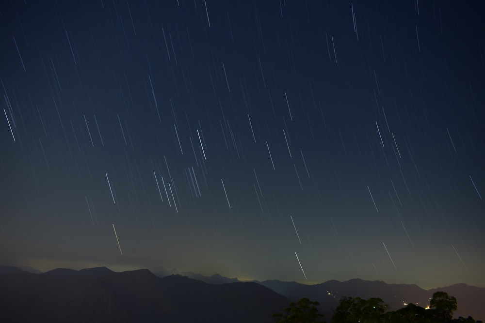 the night sky with stars above a mountain range