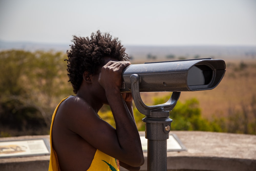 man using coin operated telescope during daytime