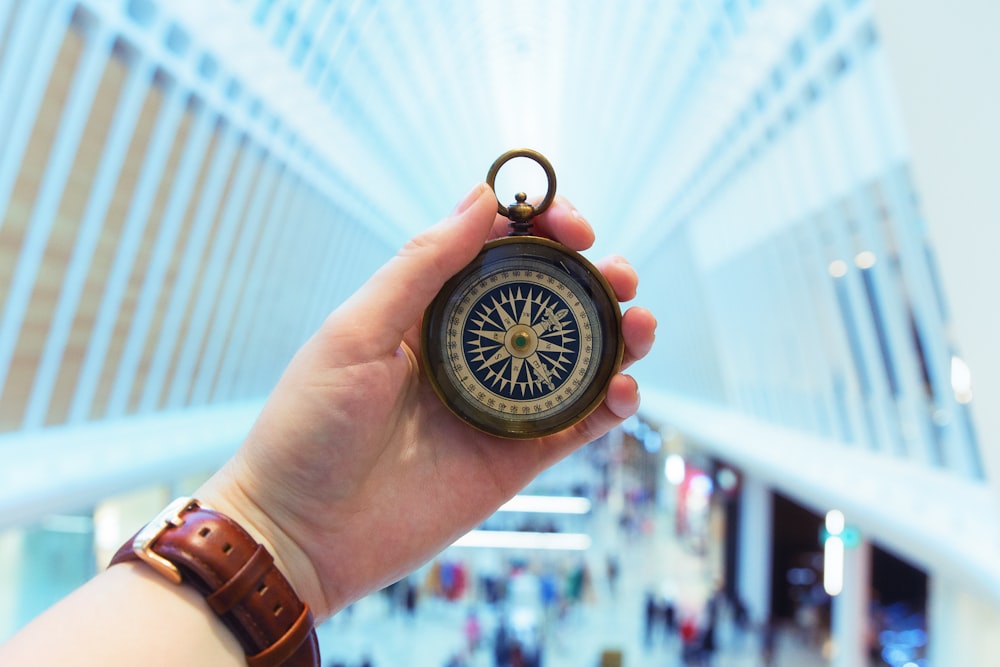 person holding brass-colored compass