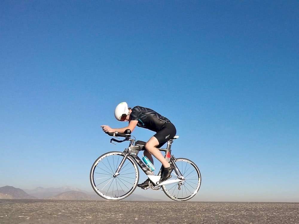 Hombre que monta en bicicleta de carretera gris durante el día