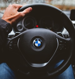 person holding BMW vehicle steering wheel