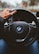 person holding BMW vehicle steering wheel
