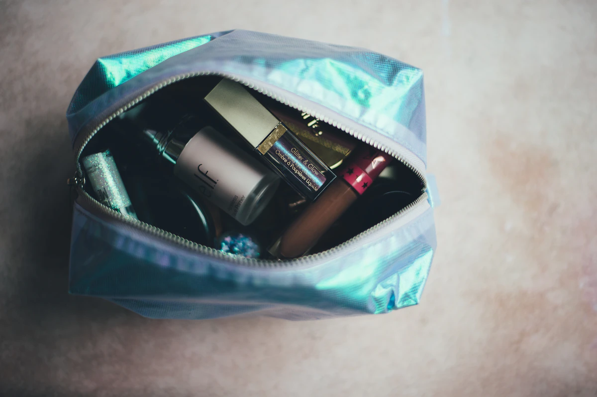 Iridescent toiletry pouch unzipped, full of makeup and skincare
