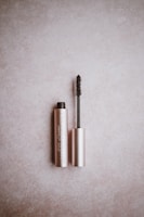 Soft, fluttery lashes arranged next to a rose gold mascara tube on a light pink surface