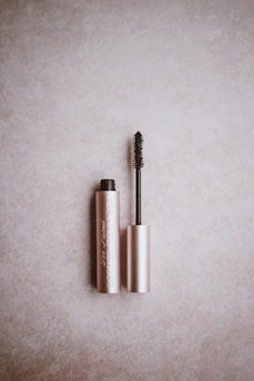 Soft, fluttery lashes arranged next to a rose gold mascara tube on a light pink surface