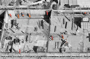 Aerial view of construction workers in orange high-visibility clothing on a concrete building site