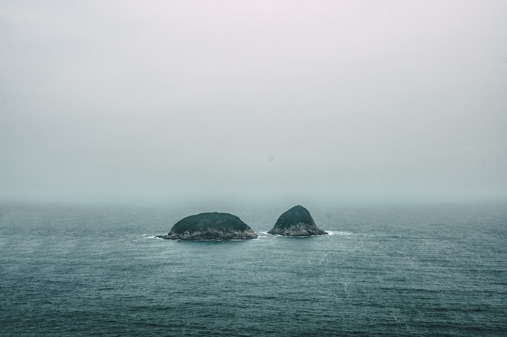昼間の海の真ん中にある2つの灰色の岩層