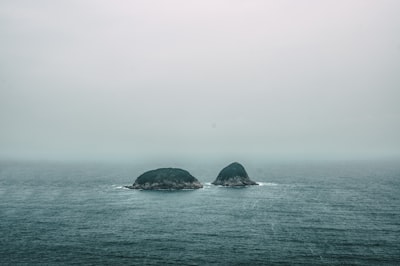 two gray rock formations on the middle of sea at daytime boundless google meet background