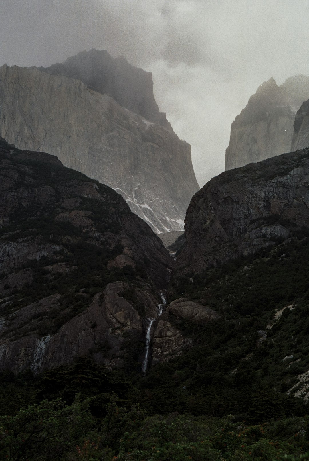 waterfall in the middle of two mountains during a foggy weather