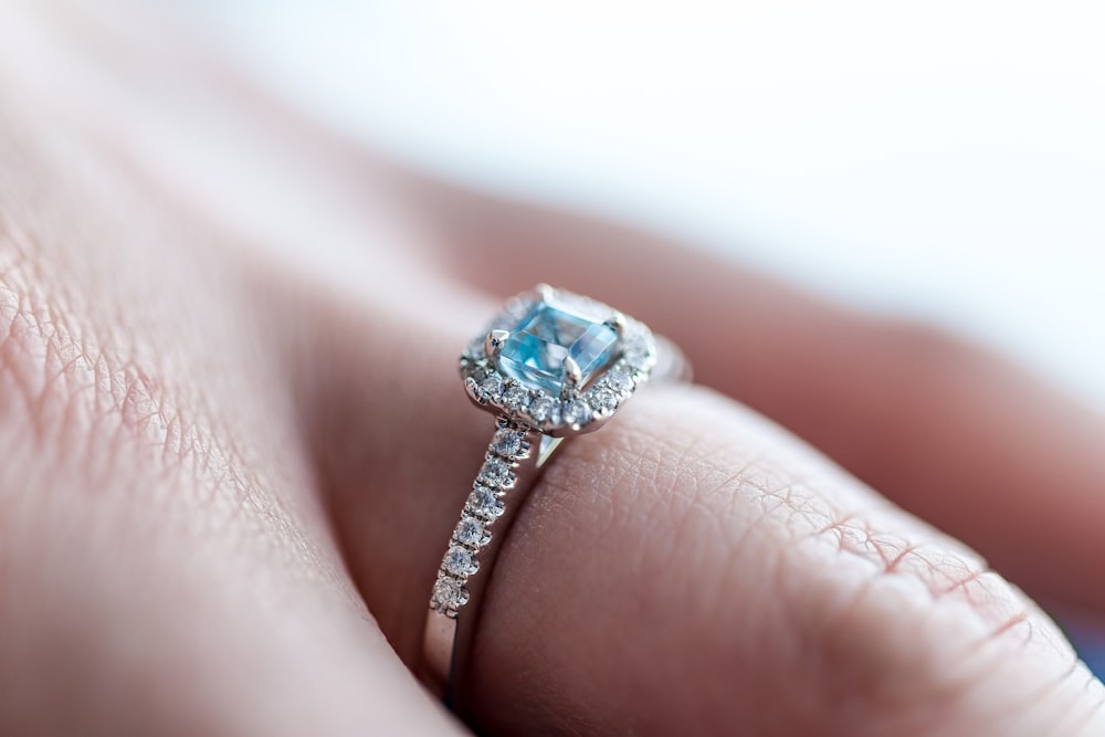 person showing silver-colored ring with gemstone