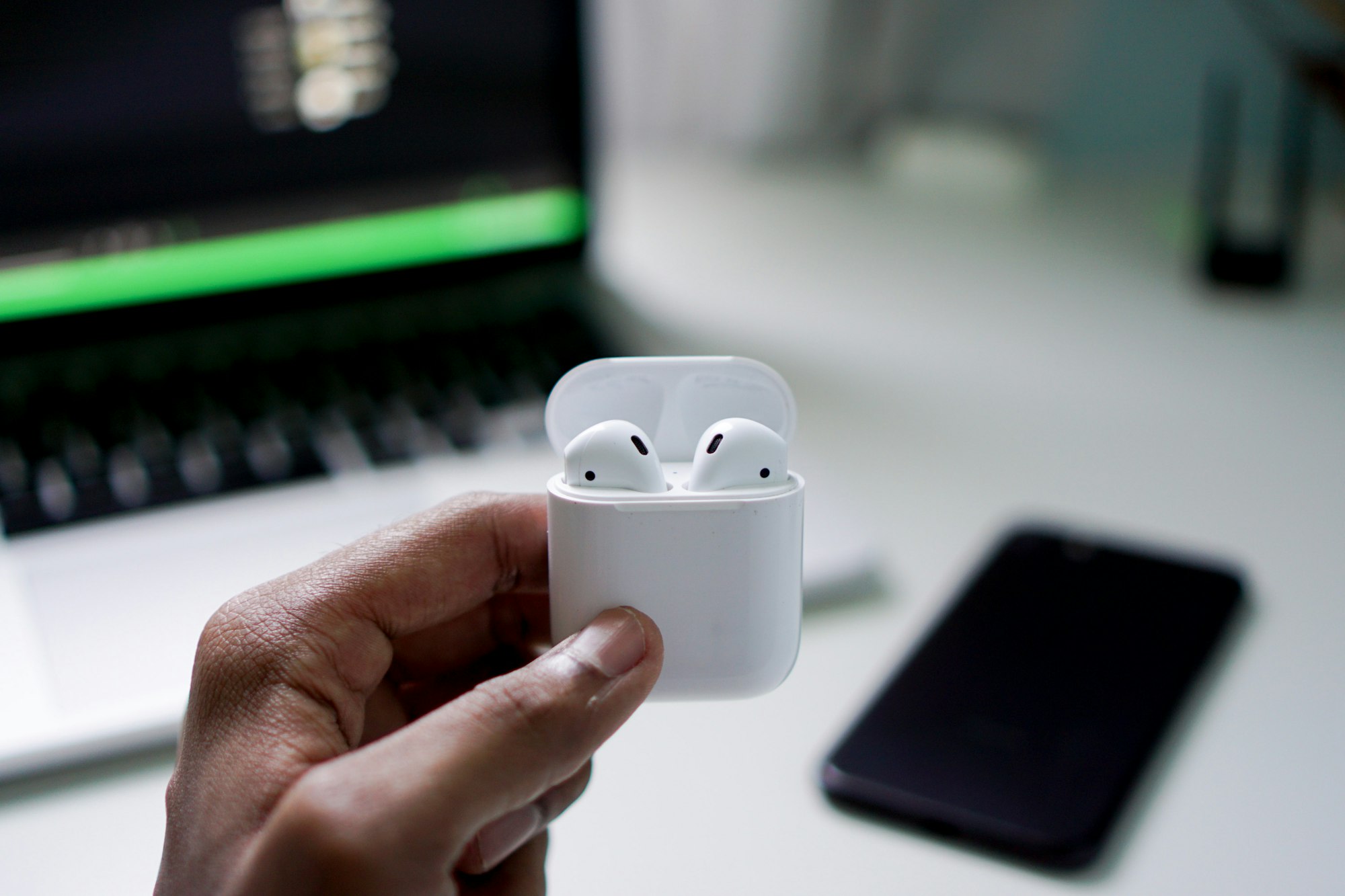 A person holding the Aipods, the bluetooth-enabled earphones of Apple 
