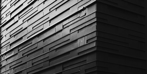 Close-up of a modern building façade featuring textured terracotta panels with sharp geometric patterns.
