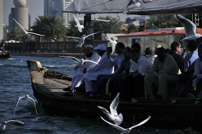 A group of friends laughing on a yacht, with seagulls flying overhead.