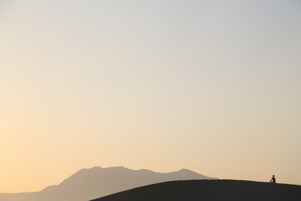 photo of person sitting on mountain