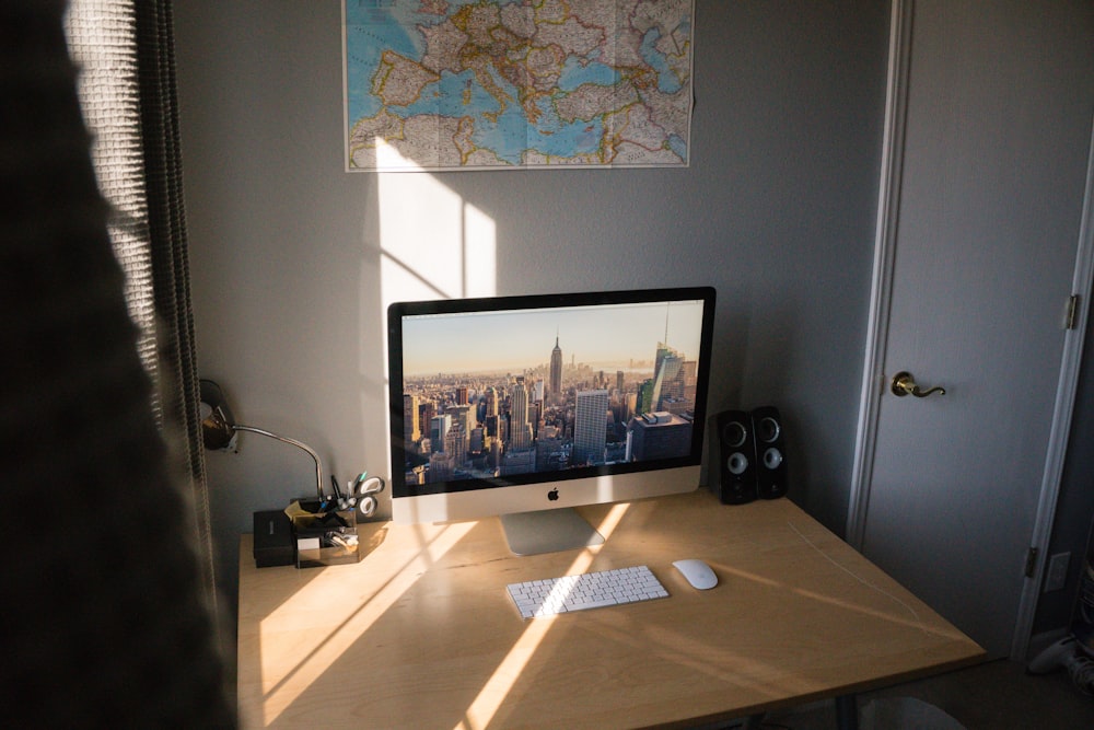 베이지색 나무 책상 위에 은색 iMac을 켰습니다.