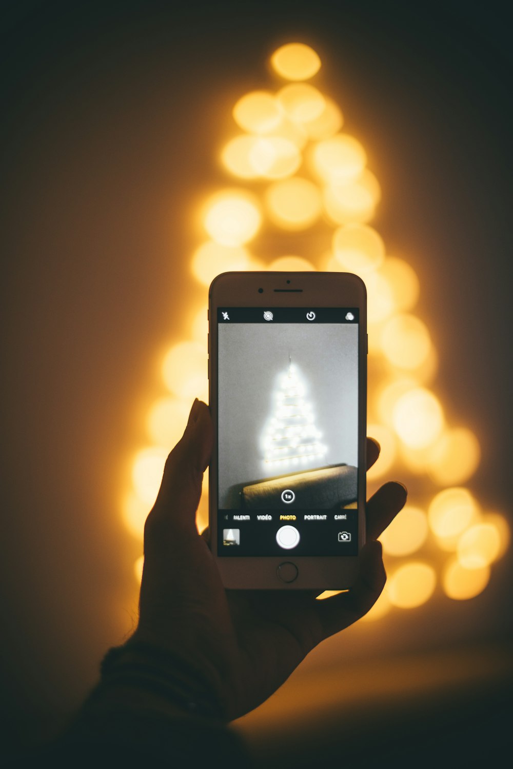 person capturing image of lighted Christmas tree