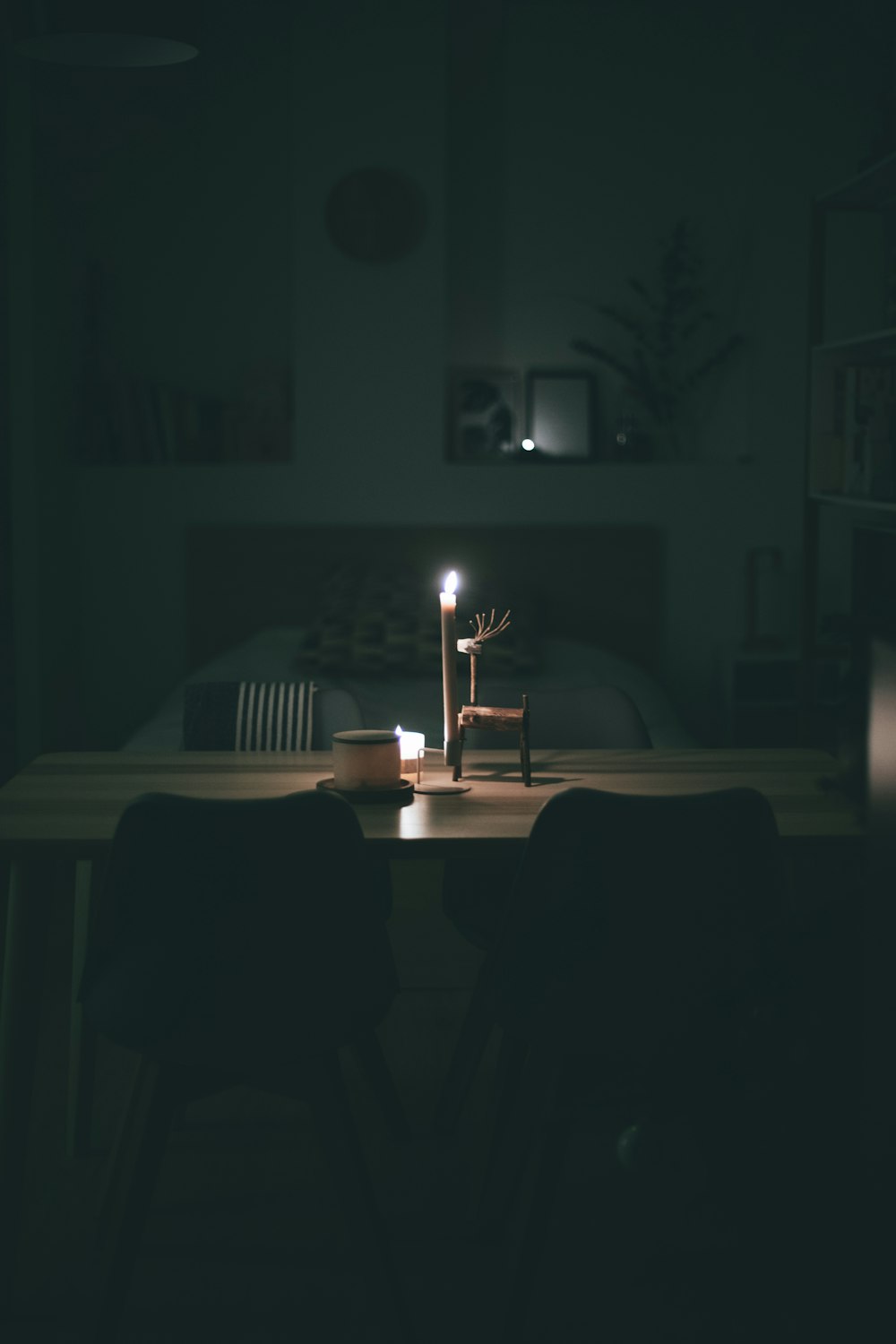 lighted white pillar candle near ceramic mug on wooden table