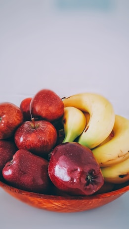 A cheerful person enjoying a bowl of assorted fresh fruit from Banana's online store.