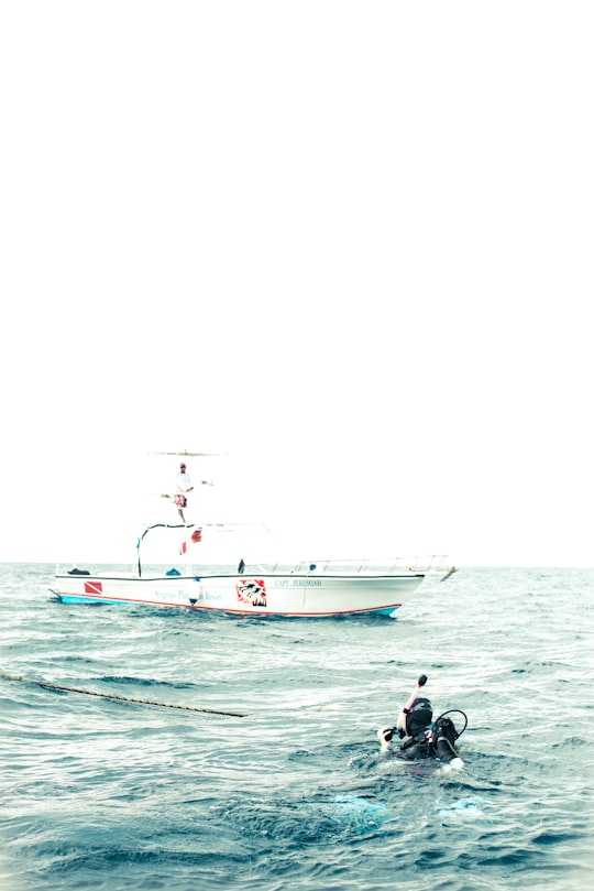 black person scuba diving near white boat in Roatán Honduras