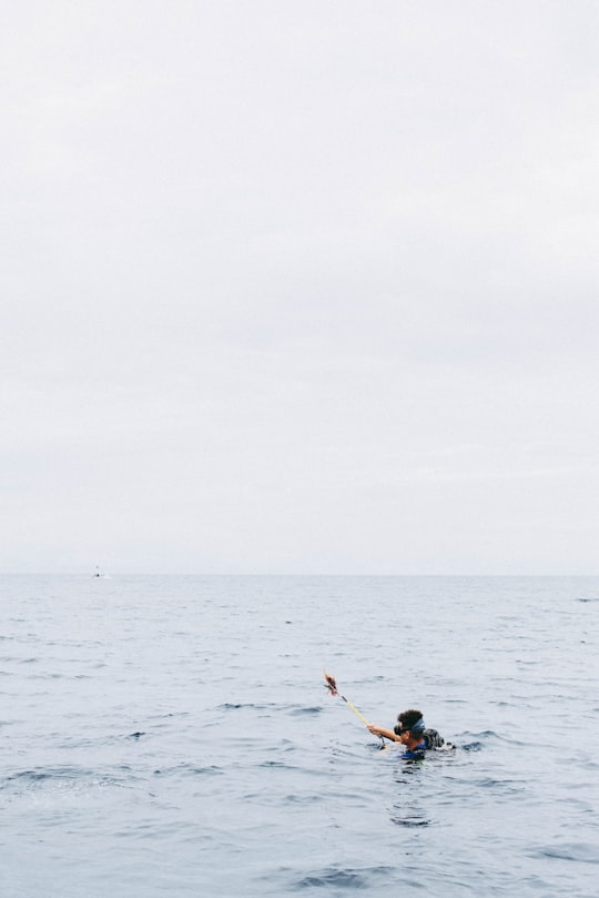 man holding rod while on water in Roatán Honduras