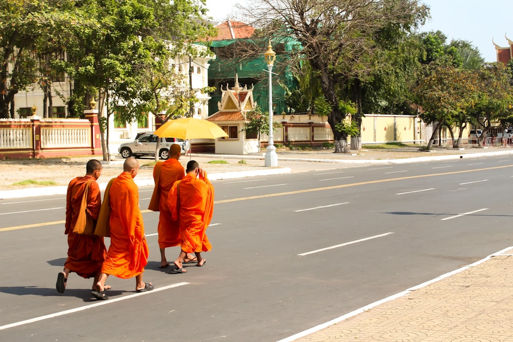 people in orange robe walking on gray asphalt road during daytime