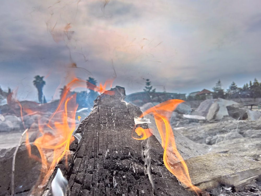 bonfire near rocks under gray clouds during daytime