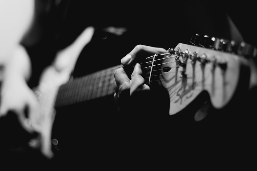 Graustufenfotografie einer Person, die E-Gitarre spielt