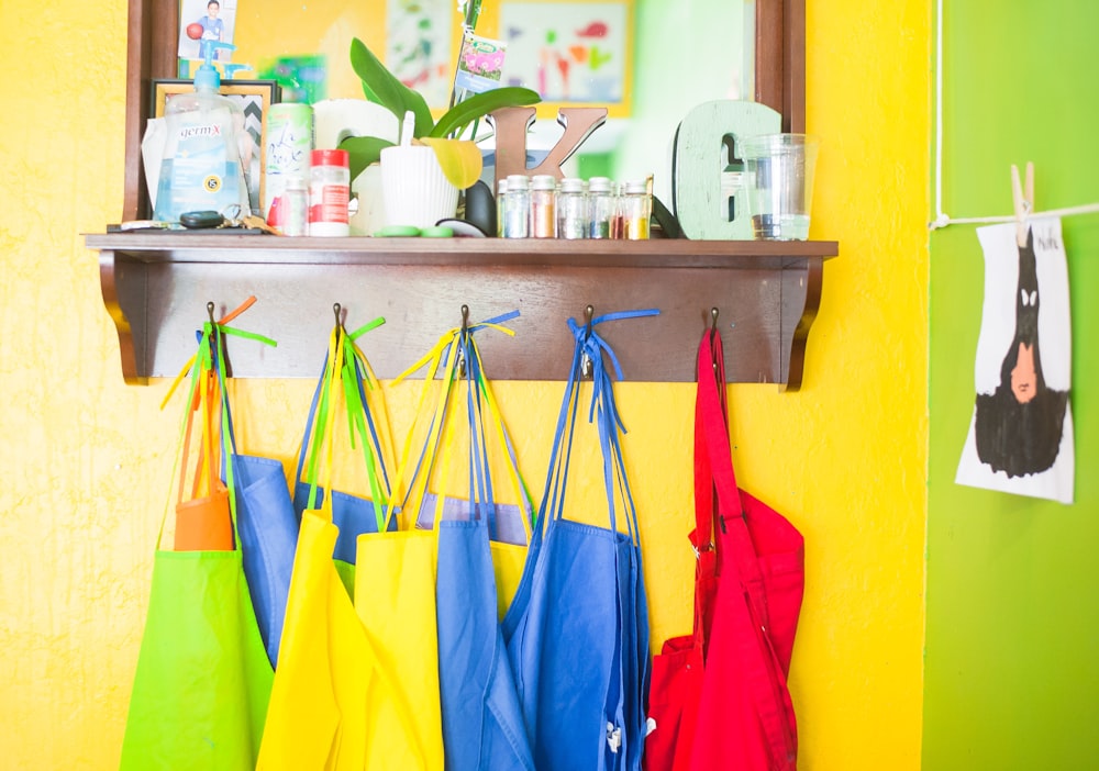 lote de bolsas de colores variados colgado en un estante de pared de madera marrón