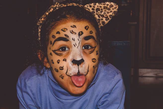 Close-up of a child's face painted as a fierce tiger with bright orange and black stripes.