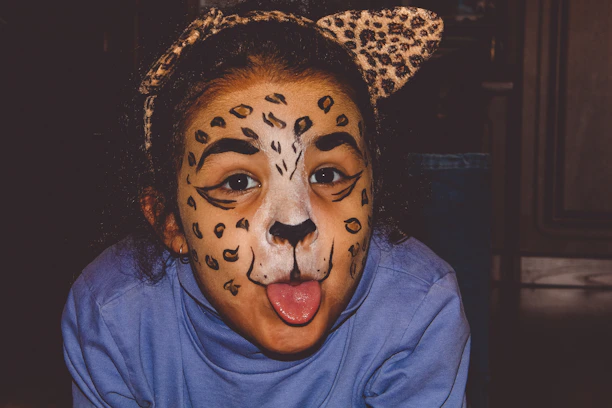 Close-up of a child's face painted as a fierce tiger with bright orange and black stripes.
