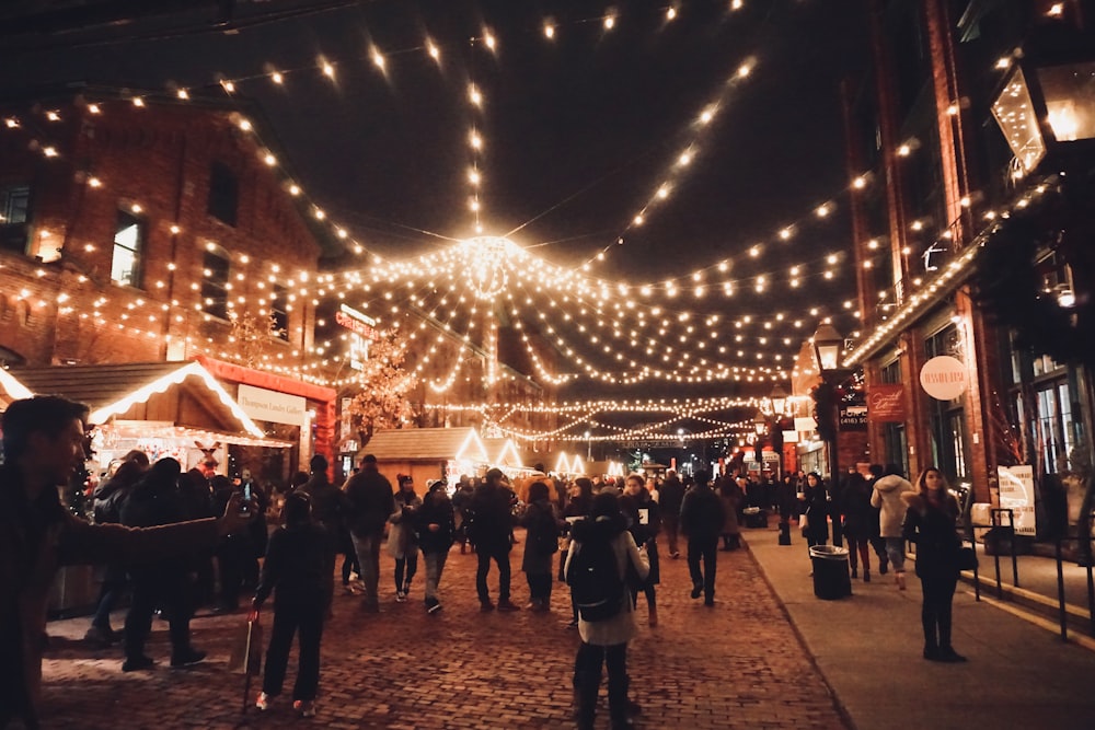 people on road under string lights during nighttime