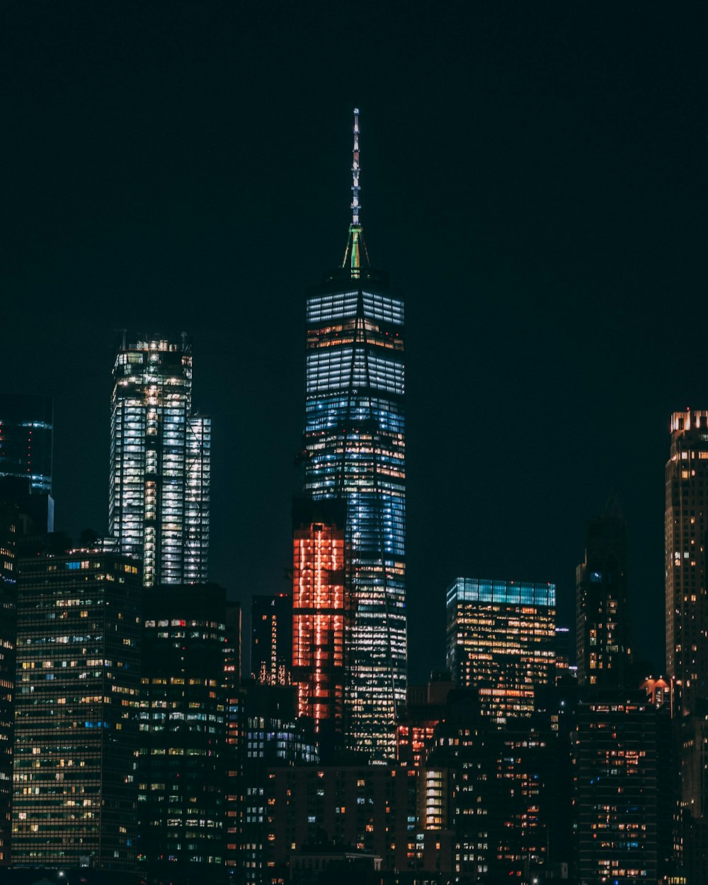 Immeubles de grande hauteur avec des lumières allumées sous un ciel noir pendant la nuit