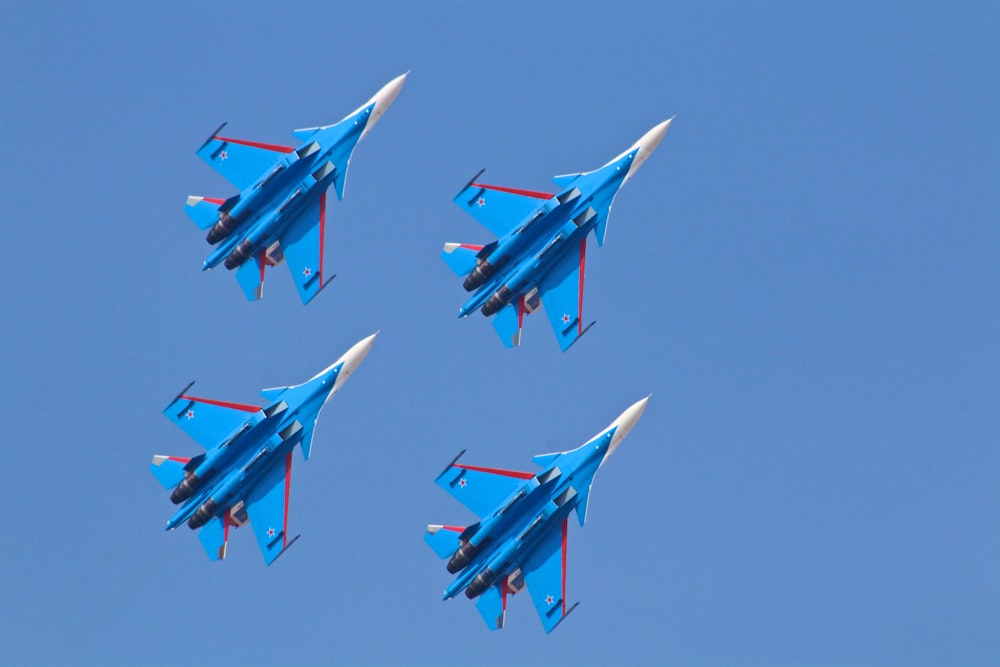 four blue fighter planes under blue sky