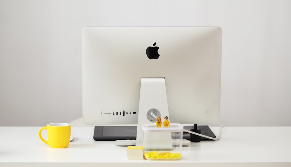 silberner iMac neben gelbem Becher