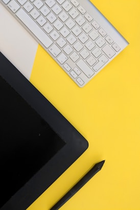 gray Apple wireless keyboard beside black tablet computer and stylus pen