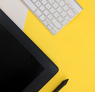 gray Apple wireless keyboard beside black tablet computer and stylus pen