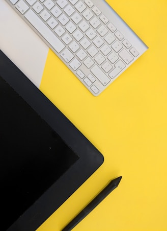 gray Apple wireless keyboard beside black tablet computer and stylus pen