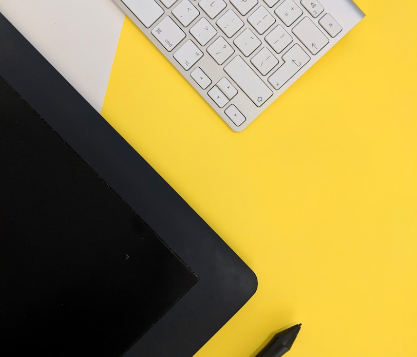 gray Apple wireless keyboard beside black tablet computer and stylus pen