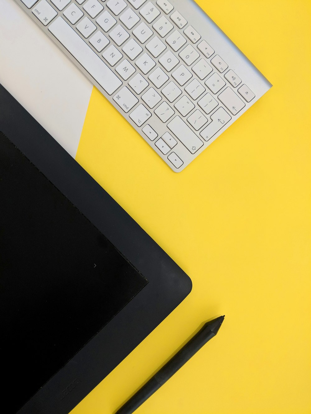 회색 Apple 무선 키보드 옆에 검은 색 태블릿 컴퓨터와 스타일러스 펜