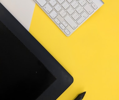 gray Apple wireless keyboard beside black tablet computer and stylus pen