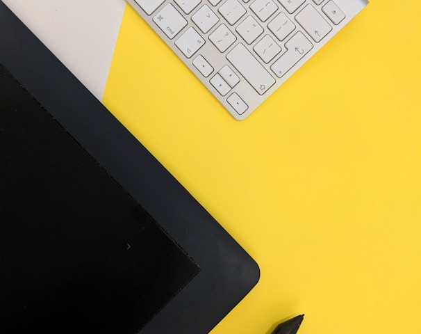 gray Apple wireless keyboard beside black tablet computer and stylus pen