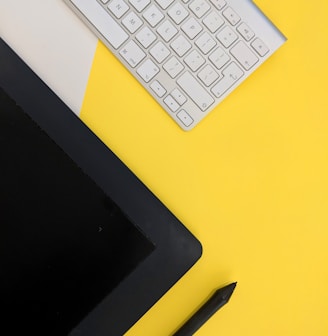 gray Apple wireless keyboard beside black tablet computer and stylus pen