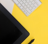 gray Apple wireless keyboard beside black tablet computer and stylus pen