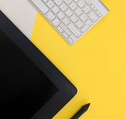 gray Apple wireless keyboard beside black tablet computer and stylus pen