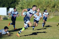 Close-up of a rugby player from the New Zealand All Blacks sprinting with the ball.
