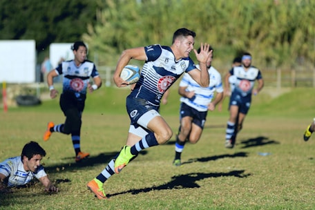 A dynamic rugby player sprinting with the ball on a vibrant stadium field.