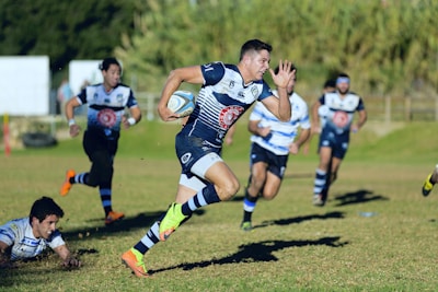 Close-up of a rugby player from the New Zealand All Blacks sprinting with the ball.