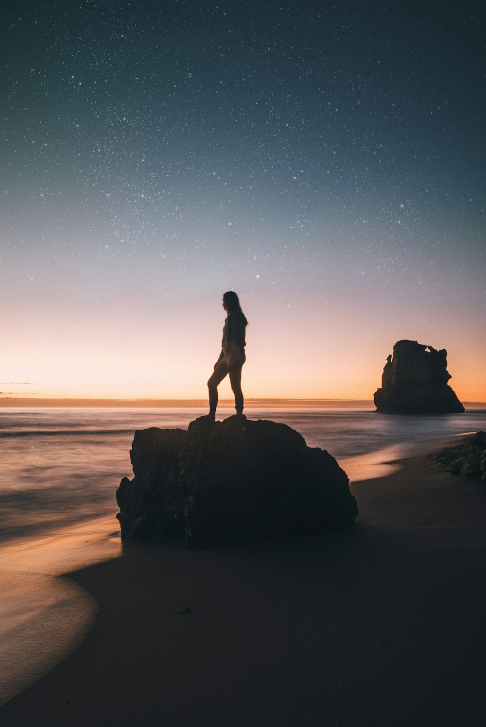 person standing on rock overlooking sea